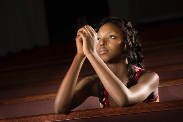 God hears prayers: A woman kneeling and praying to God