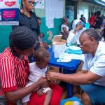 Mother and child with UNICEF health worker Ezeugwu at a measles vaccination injection campaign
